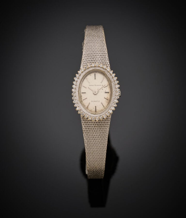 BRACELET MONTRE ovale de dame en or gris (750‰). Lunette sertie de petits amant…