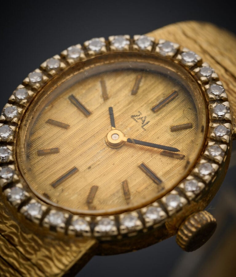 BRACELET MONTRE ovale de dame en or jaune (750‰) ciselé. Lunette sertie de diam…
