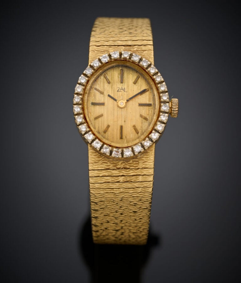 BRACELET MONTRE ovale de dame en or jaune (750‰) ciselé. Lunette sertie de diam…