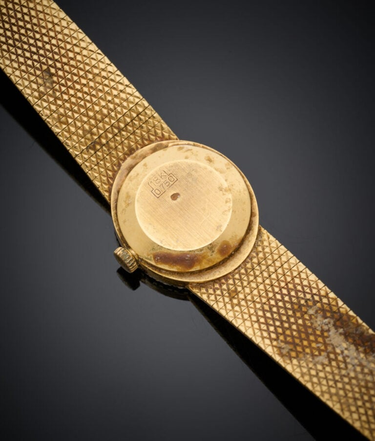 BRACELET MONTRE ovale de dame en or jaune (750‰) ciselé. Lunette sertie de diam…