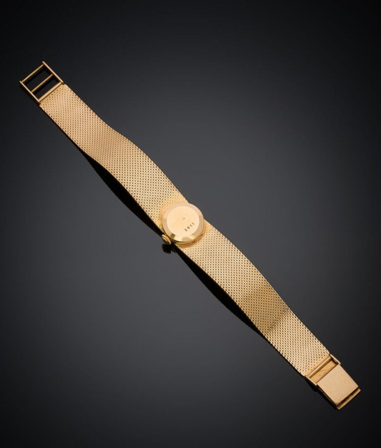 BRACELET MONTRE "ruban" ronde de dame en or jaune (750‰). Cadran crème, chiffre…