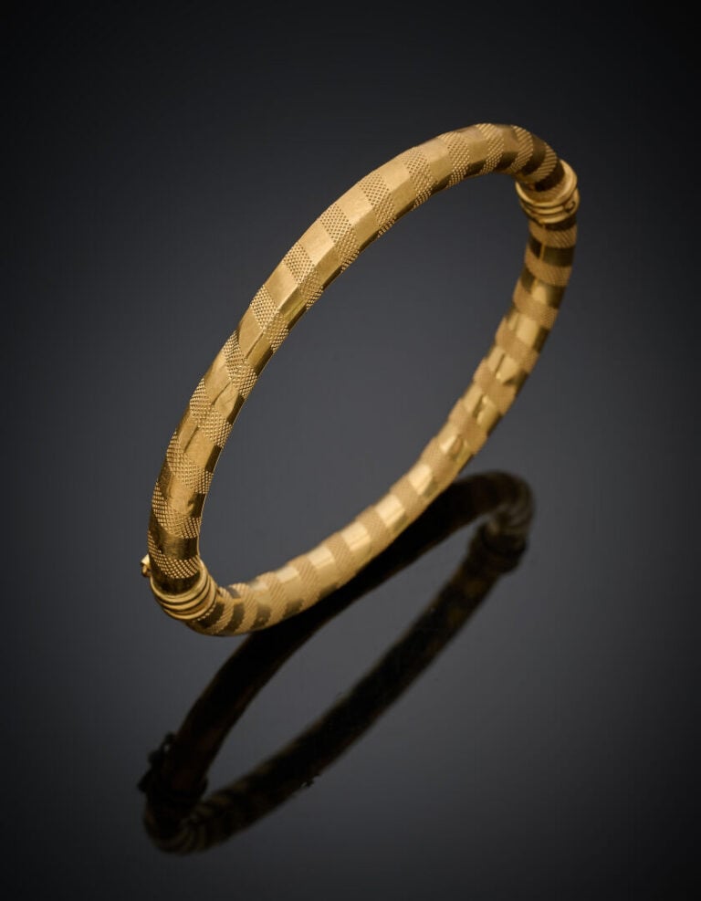 BRACELET rigide ouvrant en or jaune (750‰) guilloché. Chocs. - Long.: 17,8 cm.…