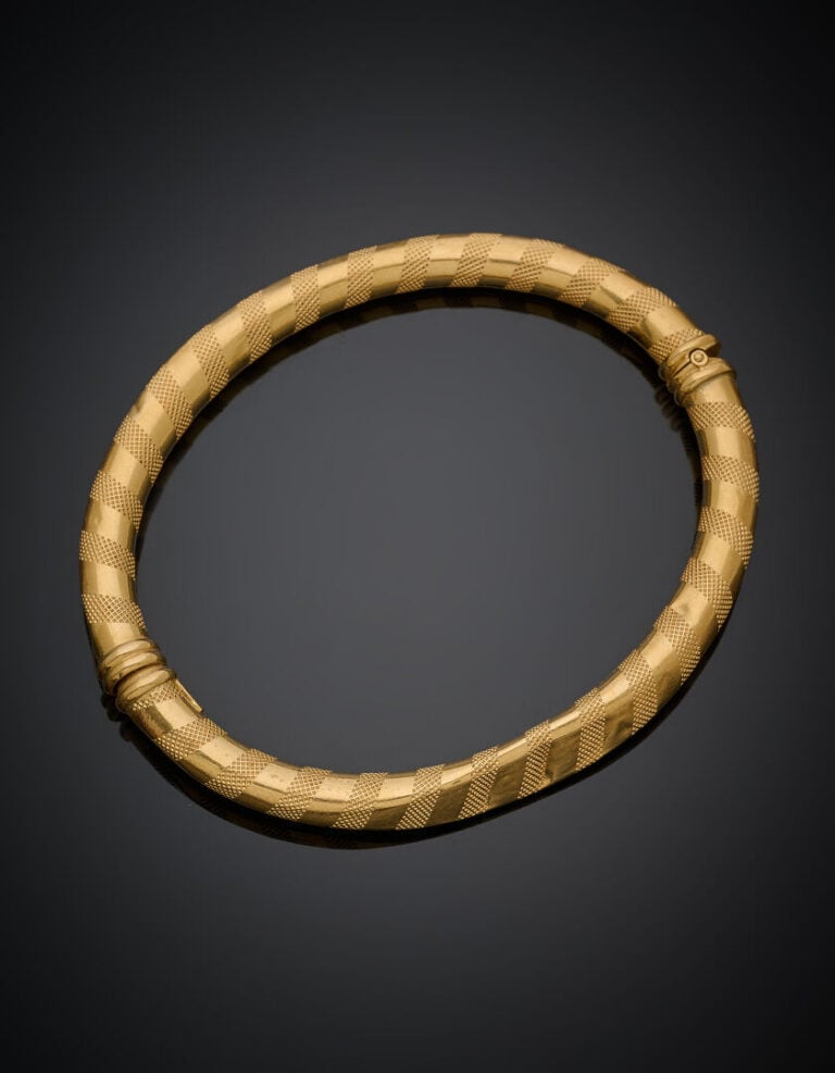 BRACELET rigide ouvrant en or jaune (750‰) guilloché. Chocs. - Long.: 17,8 cm.…