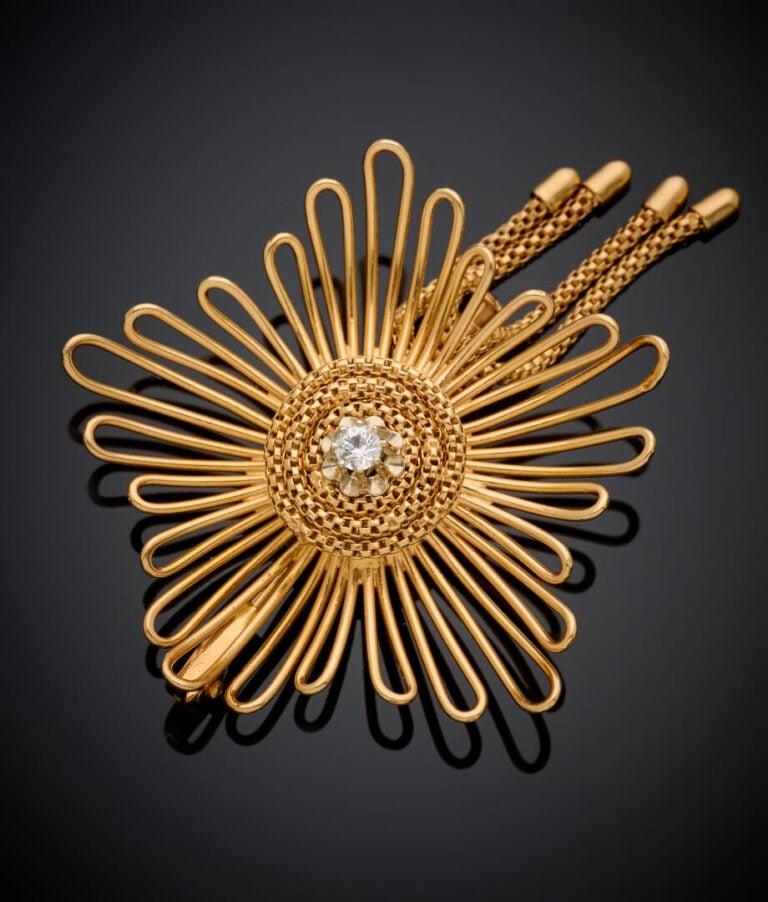 BROCHE "fleur" en fils d'or jaune (750‰) centré d'une pierre blanche, retenant…