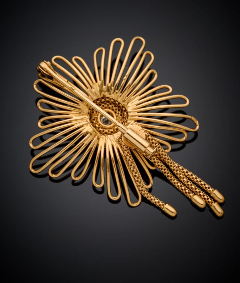 BROCHE "fleur" en fils d'or jaune (750‰) centré d'une pierre blanche, retenant…