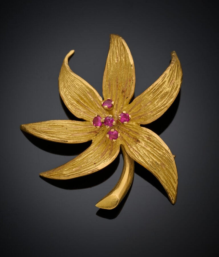 BROCHE "fleur" en or jaune (750‰) ciselé, serti de pierres rouges rondes. - Tra…