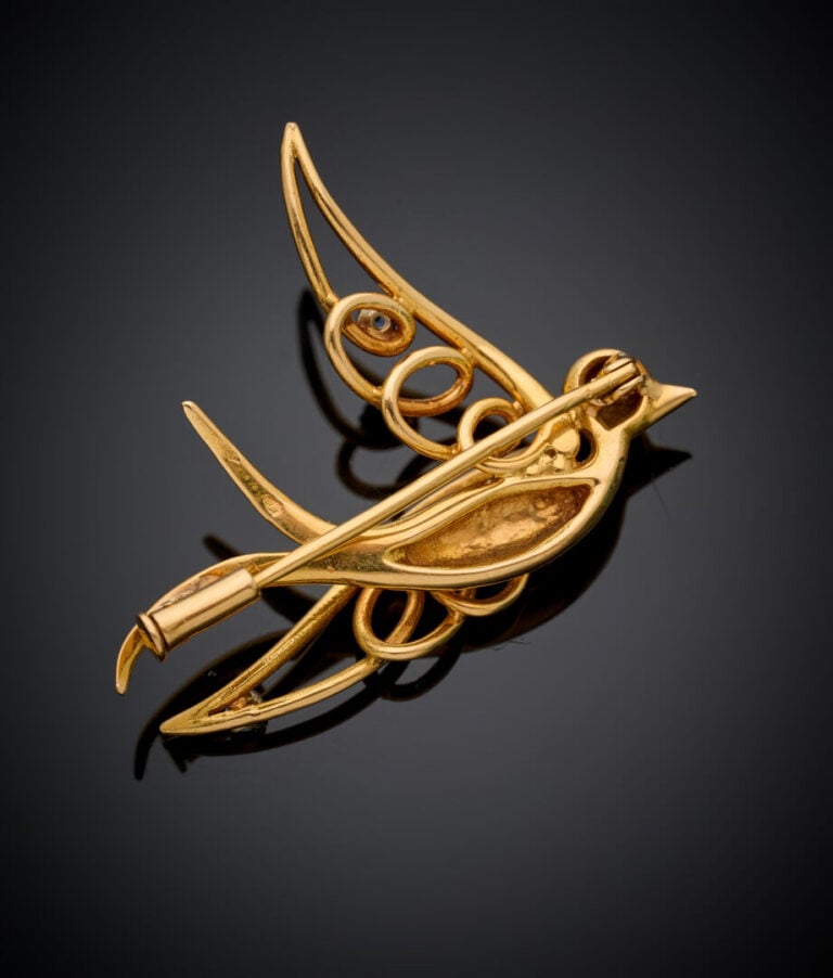 BROCHE "oiseau en vol" en or jaune (750‰), les ailes ajourées ponctuées de peti…