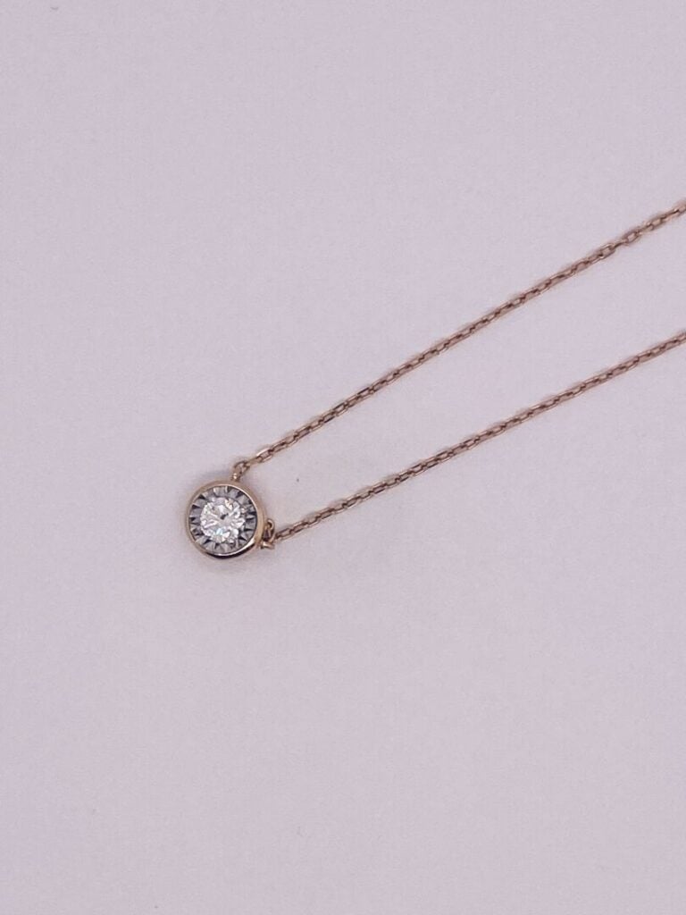 COLLIER et sa chaînette en or rose et or gris (750‰) guilloché, retenant un dia…