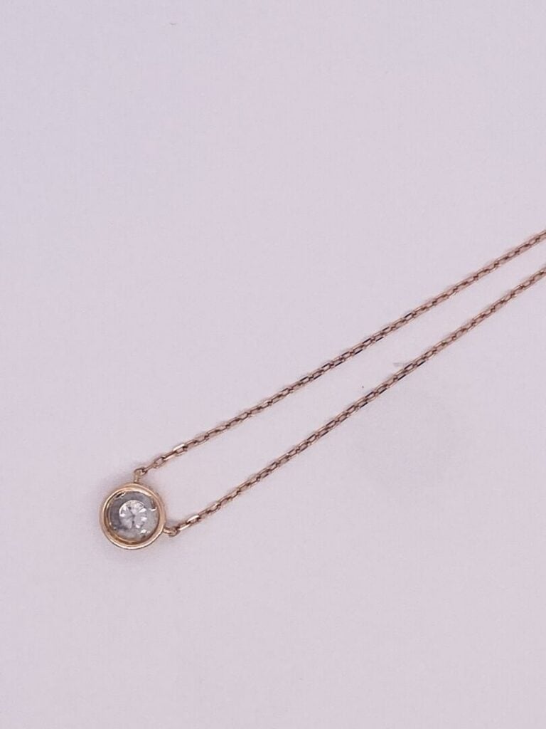 COLLIER et sa chaînette en or rose et or gris (750‰) guilloché, retenant un dia…