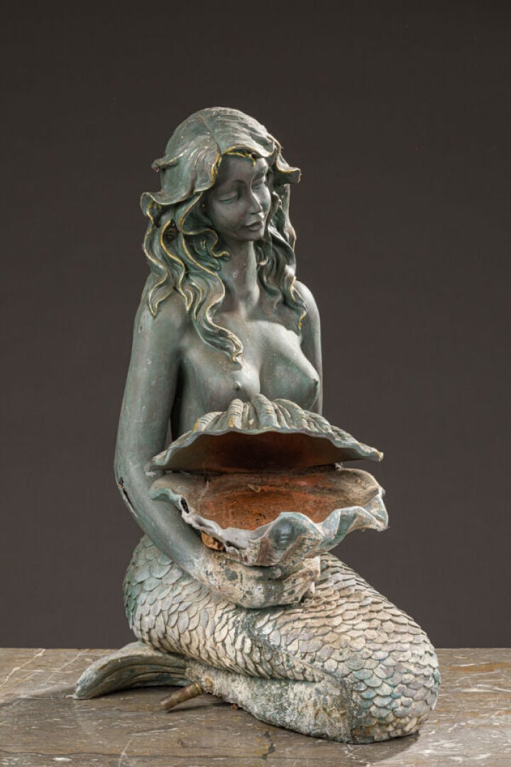 Fontaine en métal patiné vert stylisant une sirène agenouillée retenant dans se…
