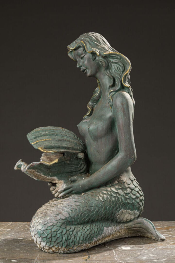 Fontaine en métal patiné vert stylisant une sirène agenouillée retenant dans se…