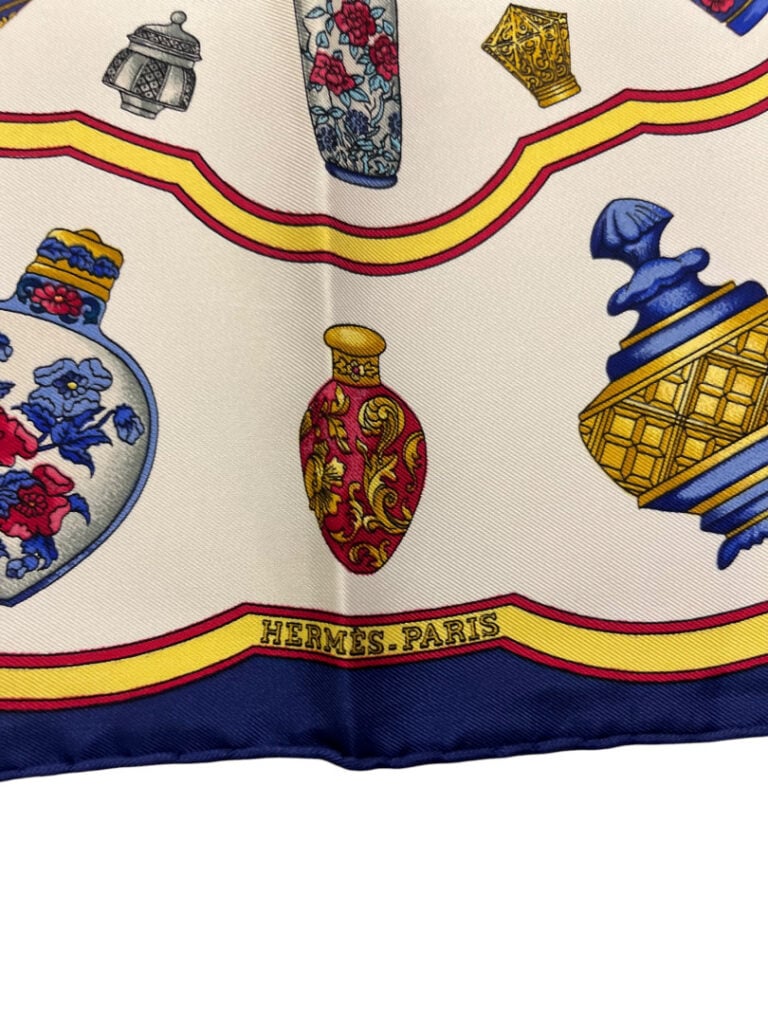 HERMÈS - Petit carré Gavroche en soie à motifs de flacons de parfums sur fond b…