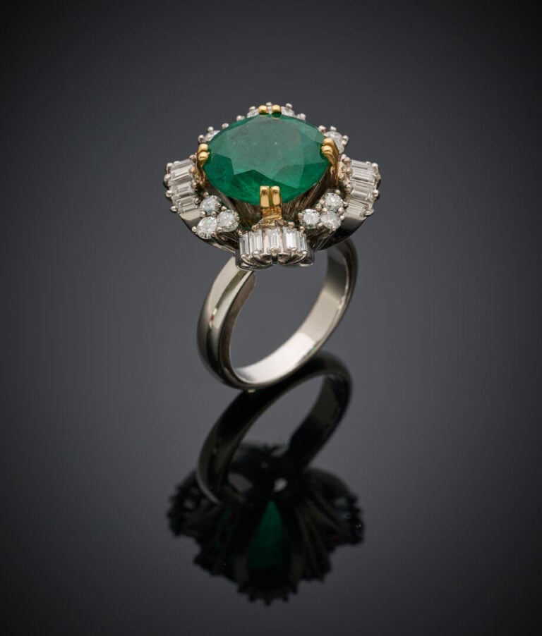 Importante BAGUE en or jaune et or gris (750‰) serti d'une émeraude ronde entou…