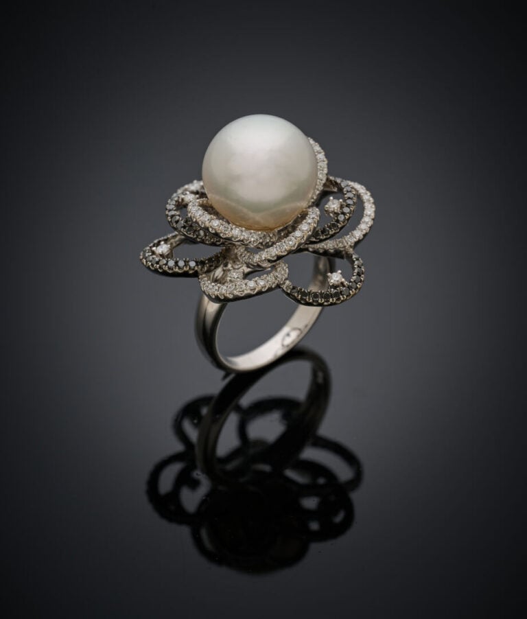 Importante BAGUE "fleur" en or gris et or noirci (750‰) ajouré, centrée d'une p…