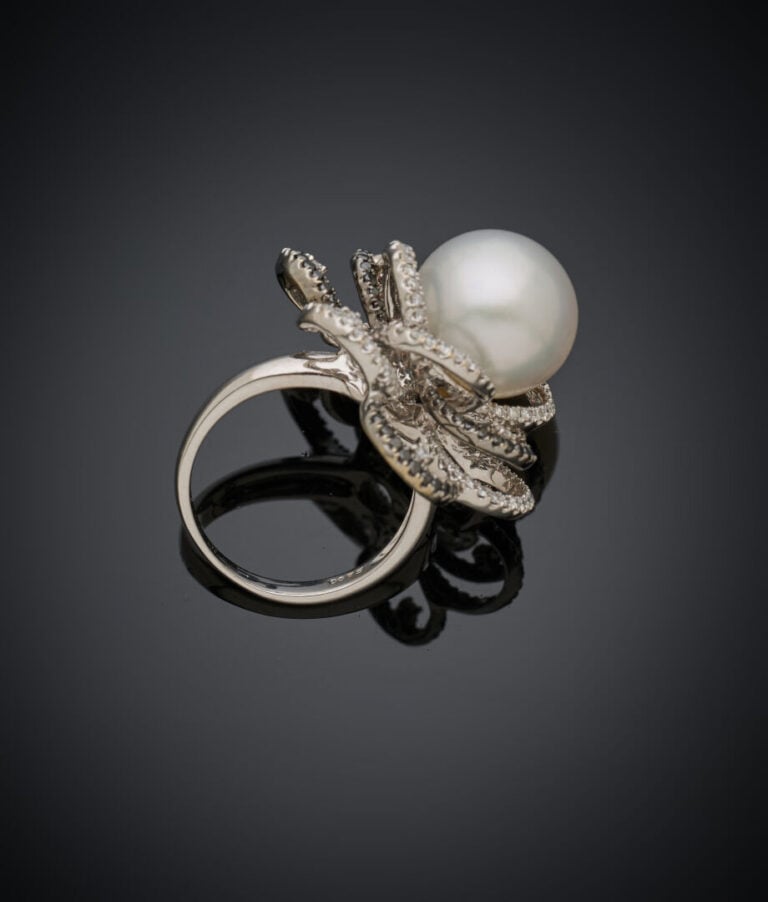 Importante BAGUE "fleur" en or gris et or noirci (750‰) ajouré, centrée d'une p…