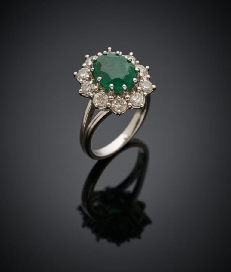Importante BAGUE "marguerite" en or gris (750‰) serti d'une émeraude ovale, ent…