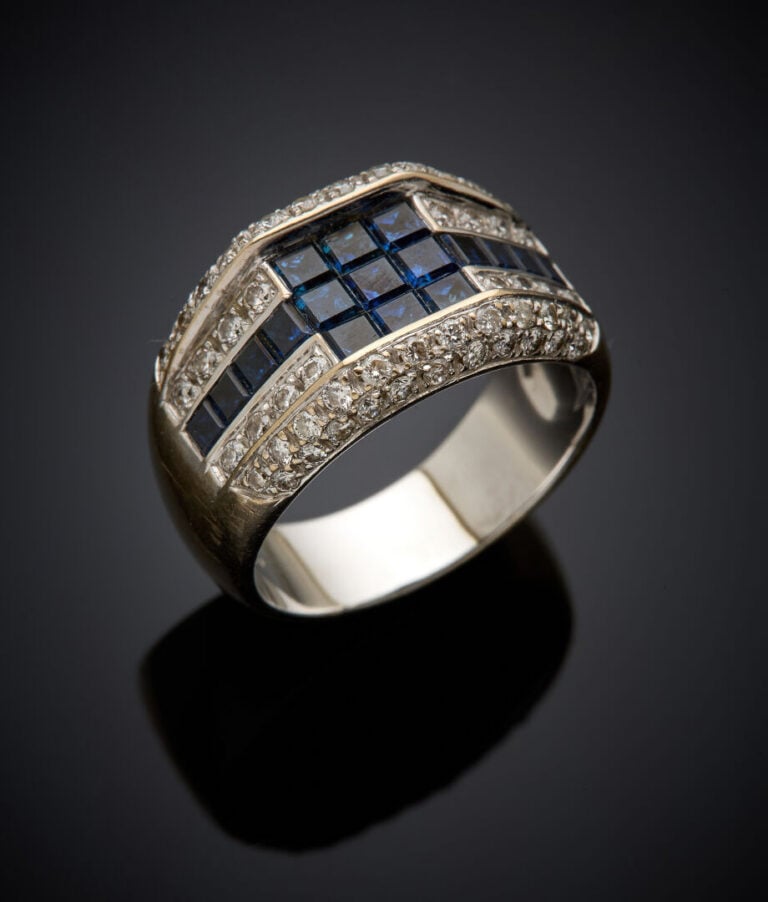 Large BAGUE en or gris (750‰) ornée de saphirs calibrés en serti invisible, ent…