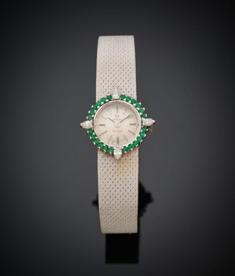 OMEGA - BRACELET MONTRE ronde de dame en or gris (750‰). Lunette sertie d'émera…