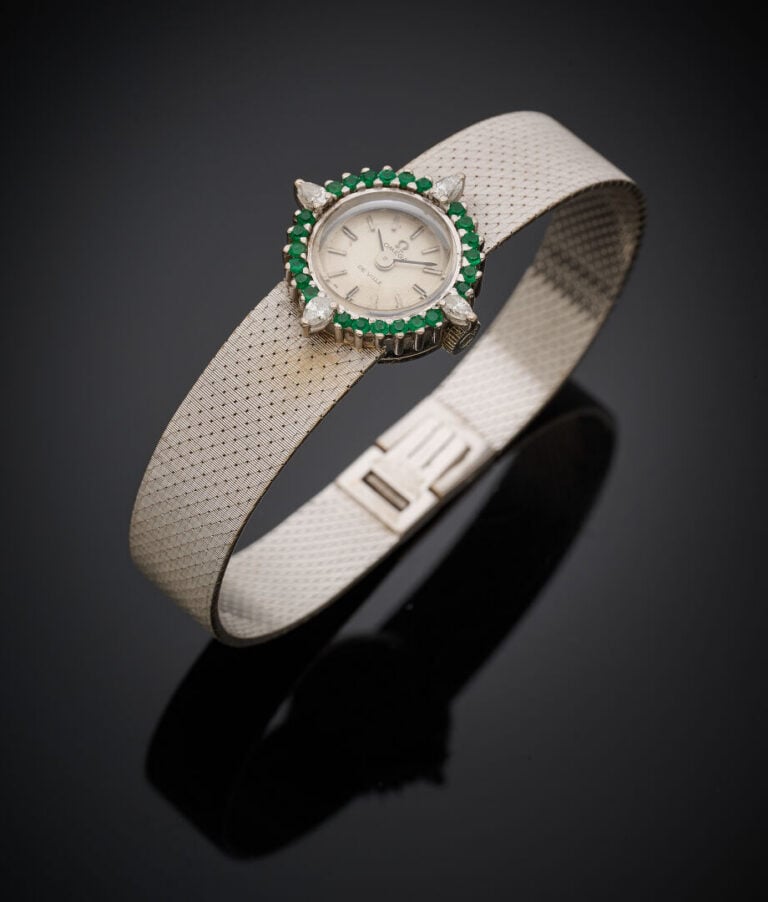 OMEGA - BRACELET MONTRE ronde de dame en or gris (750‰). Lunette sertie d'émera…