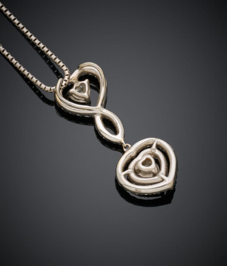 PENDENTIF "deux cœurs" et sa chaînette en or gris (750‰) ajouré, serti de deux…