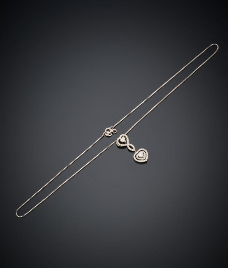 PENDENTIF "deux cœurs" et sa chaînette en or gris (750‰) ajouré, serti de deux…
