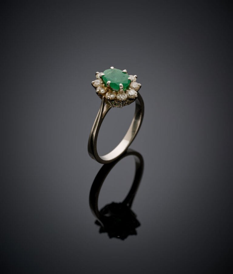 Petite BAGUE "marguerite" en or gris (750‰) serti d'une émeraude ovale entourée…