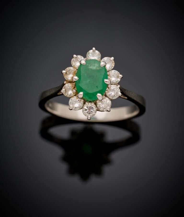 Petite BAGUE "marguerite" en or gris (750‰) serti d'une émeraude ovale entourée…